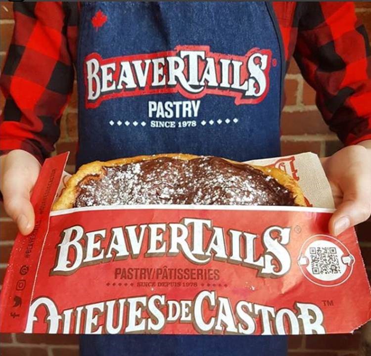 Homem segurando uma unidade de Beaver Tail, sobremesa típica do Canadá